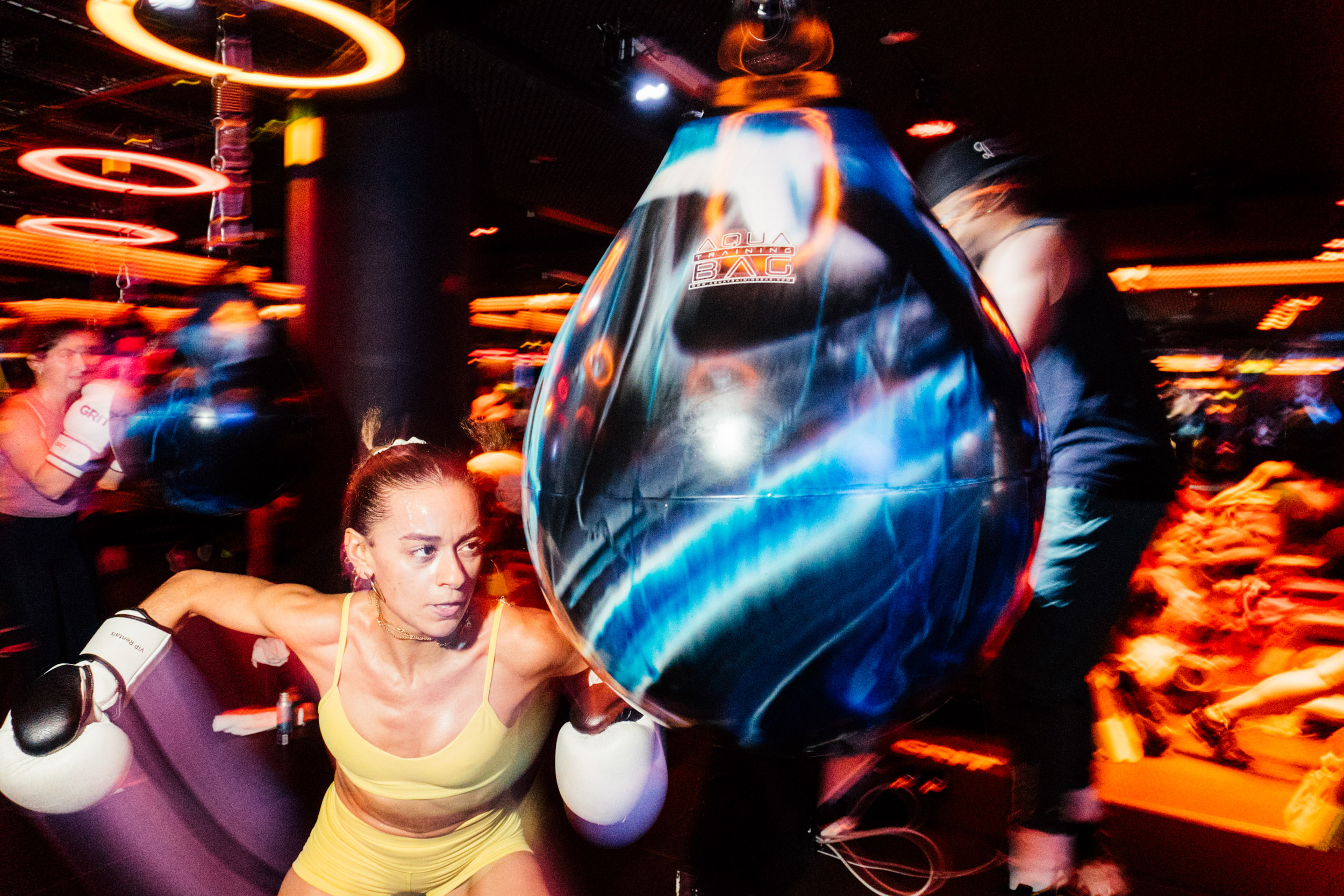 A woman winds up to punch a spherical punching bag.